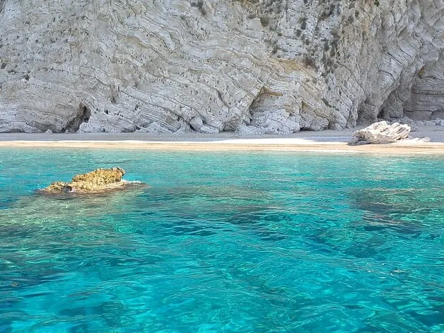 Crystal clear turquoise water near a sandy beach with impressive white cliffs