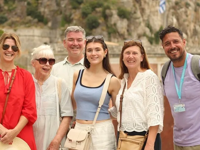 Group of six happy people smiling and posing together during a sunny tour