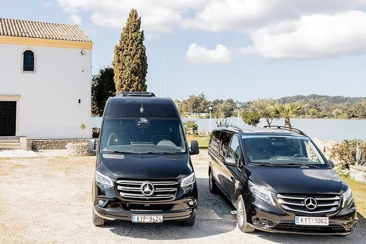 Two black Mercedes vans parked side by side near a white building