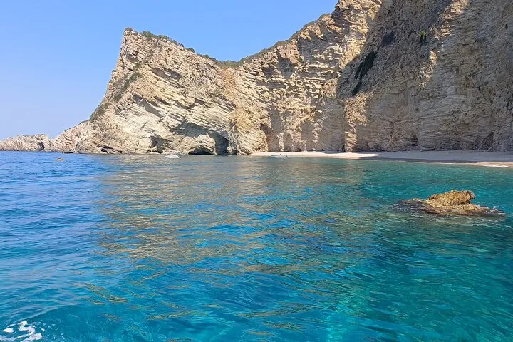 Beautiful view of steep cliffs meeting the clear blue sea with a small beach