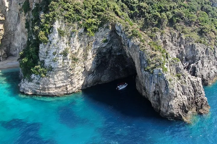 A small boat inside a large sea cave surrounded by impressive cliffs